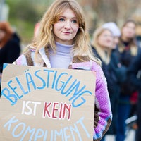 Eine Frau mit einem Schild "Belästigung ist kein Kompliment"