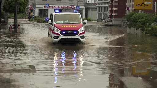 Ein Fahrzeug der DLRG fährt durch eine überflutete Straße