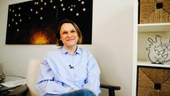 Susanne Starkmuth, eine Frau mit einer blau-weiß gestreiften Bluse, sitzt in einem Büro.