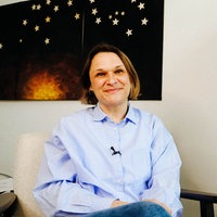 Susanne Starkmuth, eine Frau mit einer blau-weiß gestreiften Bluse, sitzt in einem Büro.