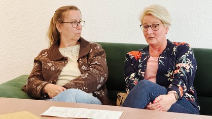 Zwei Frauen sitzen nebeneinander auf einer Couch