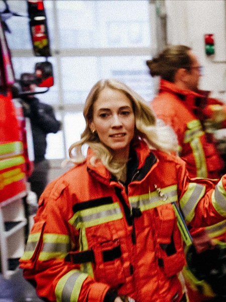 Eine Frau springt in ein Feuerwehrauto und blickt an der Kamera vorbei