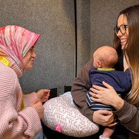 Hebamme Nadia Hassan spricht mit der frischgebackenen Mutter Metka Difortuna und ihrem kleinen Sohn Enzo