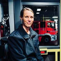 Katharina Kluge im Portrait in der Garage des Feuerwehrgebäudes. Im Hintergrund ein Feuerwehrfahrzeug.