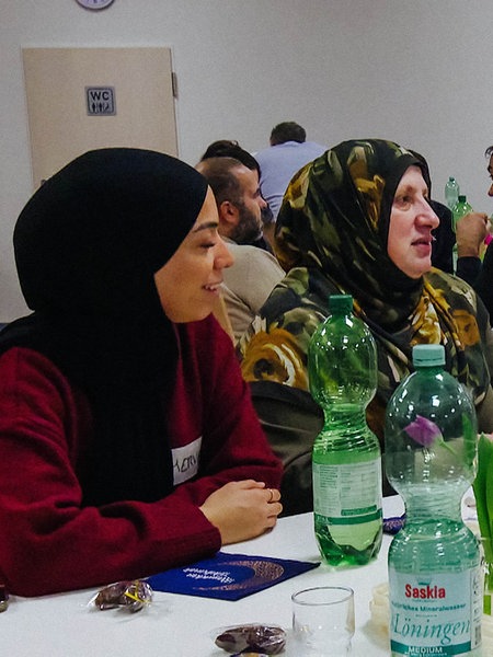 Verschiedene Menschen sitzen an einem Tisch und essen gemeinsam.