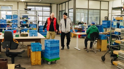 Zwei Männer gehen in einer Werkstatt entlang