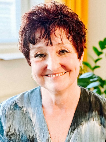 Eine Frau mit kurzen braunen Haaren lächelt in die Kamera