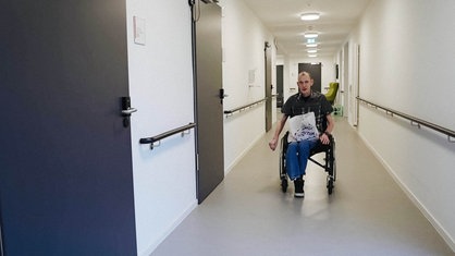 Ein Mann im Rollstuhl fährt einen Gang entlang