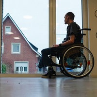 Ein Mann im Rollstuhl vor einem großen Fenster