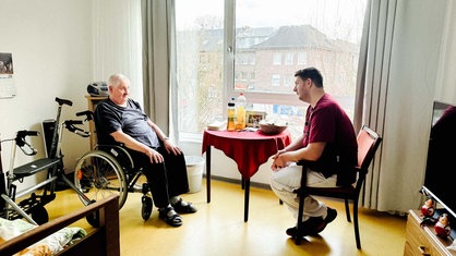v . l. Burkhard Claussen und Robbin Nilles. Sie sitzen an einem Tisch in Claussens Zimmer.