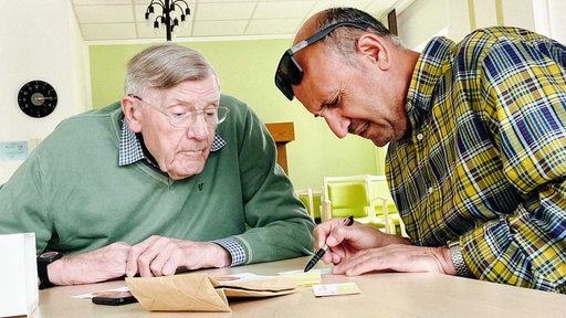 Zwei Männer sitzen für Nachhilfe an einem Tisch.