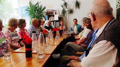 Auf dem Foto sieht man mehrere Menschen, die gemeinsam an einem Tisch sitzen.