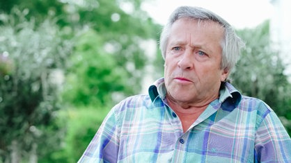 Josef Kremer sitzt im Garten und spricht.