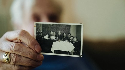 Anneliese Götte hält ein Bild in der Hand. Auf dem Bild ein Familienfoto von früher.