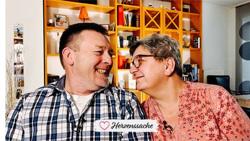 Ein älterer Mann und eine ältere Frau schauen sich verliebt an. Der Mann lacht.