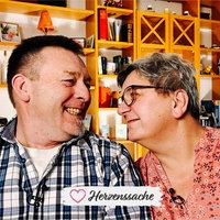 Ein älterer Mann und eine ältere Frau schauen sich verliebt an. Der Mann lacht.