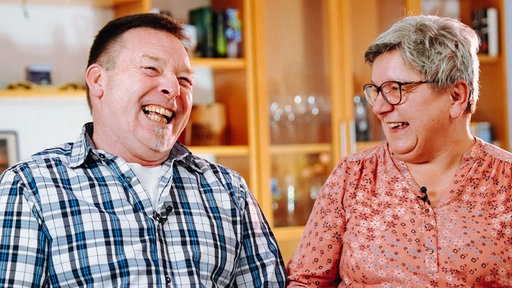 Ein älterer Mann und eine ältere Frau lachen gemeinsam.