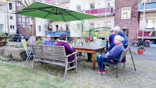 Hannah Steinfuhrt sitzt mit vielen Frauen draußen an einem Gartentisch. Sie unterhalten sich.