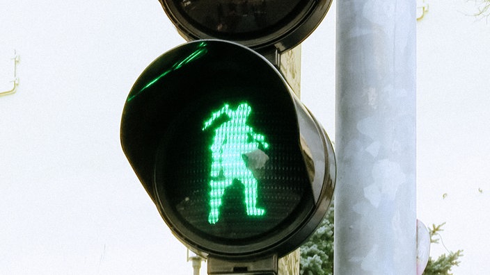 Eine grüne Ampel zeigt einen laufenden Bergmann mit Schlägel und Eisen über der Schulter.