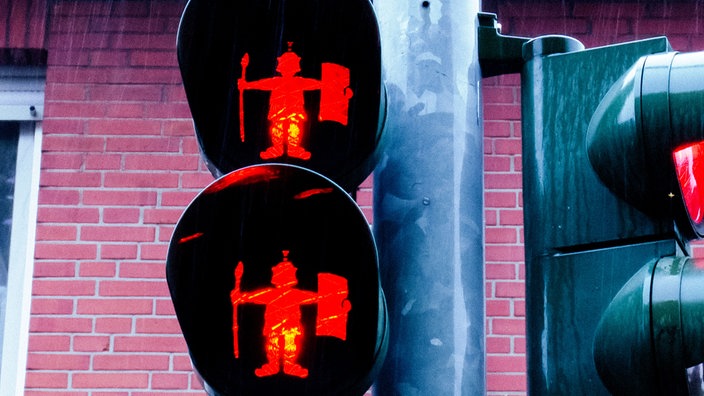Zwei rote Fußgängerampeln mit Römer-Ampelmännchen, die Helm, Schild und Speer tragen.