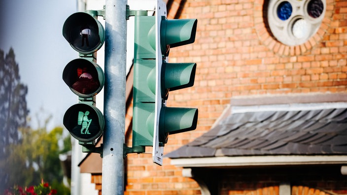 Eine grüne Ampel mit einem Pilger mit Stock und Rucksack als Ampelmännchen.