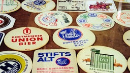 Auf einem Tisch liegen verschiedene Bierdeckel von Dortmunder Bieren.