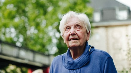 Anneliese Götte in einem blauen Pullover. Sie schaut in Richtung Himmel.