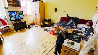 Ein Mann, der auf einem Bett liegt und Fernsehen schaut.