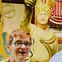 Ein Mann und eine Frau blicken in die Kamera, hinter ihnen eine Statue.