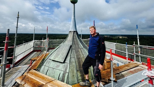 Gerald Plenter steht auf dem Gerüst der Baustelle um Schloss Raesfeld. Er steht ganz oben neben der Turmspitze. 