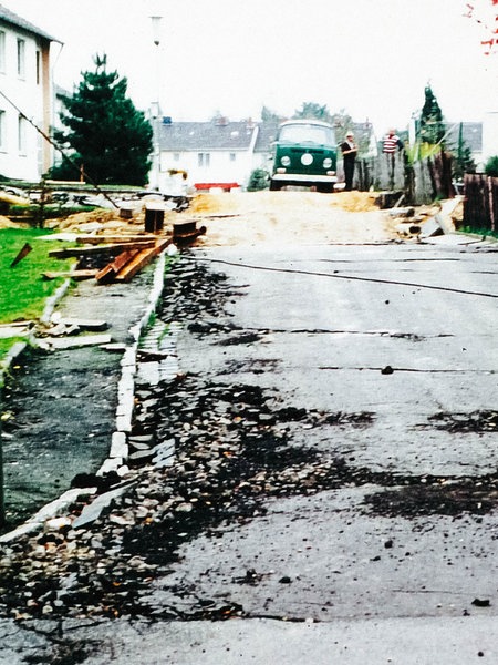 Eine Straße mit Schäden, im Hintergrund steht ein Auto