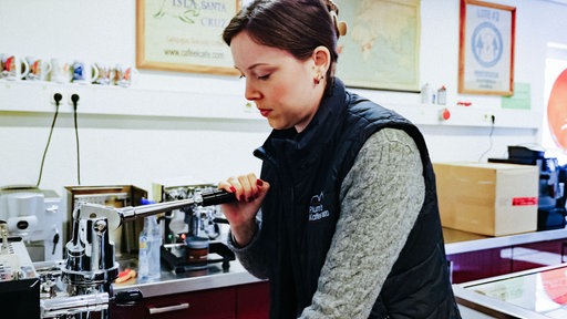 Gina Vogeler presst Kaffeepulver mit einer handbetrieben Maschine.