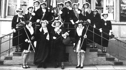 Archivaufnahme von 1937. Eine Gruppe Frauen in Karnevalsuniformen steht auf einer Treppe.