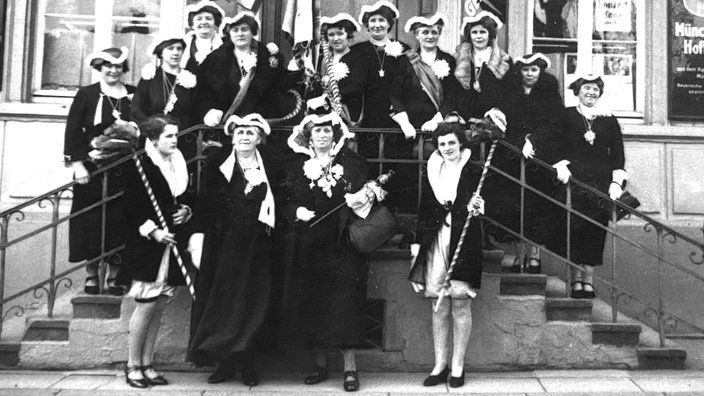 Archivaufnahme von 1937. Eine Gruppe Frauen in Karnevalsuniformen steht auf einer Treppe.