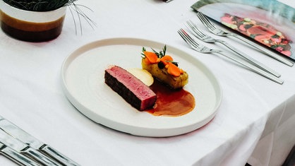 Rindfleisch und Kartoffeln auf einem weißen Teller. Das Essen ist ordentlich angerichtet.