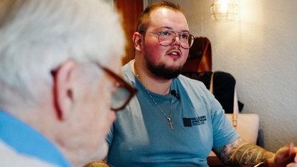 Melvin Flor sitzt am Tisch, links am Rand die Silhouette seines Großvaters.