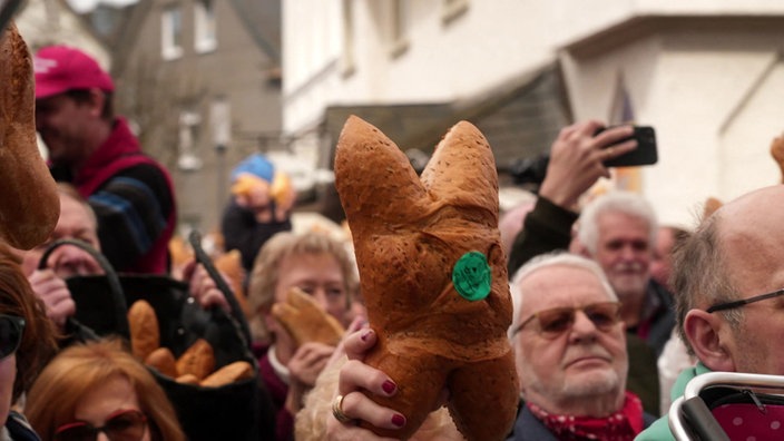 In einer Menschenmenge wird in Attendorn eine Ostersemmel in die Luft gehalten