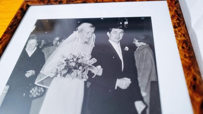 Ein gerahmtes Schwarz-Weiß-Foto, darauf ist ein junges Paar zu sehen, die Frau im weißen Brautkleid, der Mann im Anzug