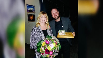Autogramm-Sammler Lars Giesen steht neben Pipi Langstrumpf - Darstellerin Inger Nilsson, die einen Blumenstrauß in der Hand hält.