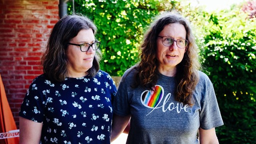 Claire und Andrea Stark Arm in Arm. Andrea trägt ein T-Shirt mit einem Herz in Regenbogenfarben.