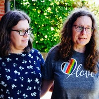 Claire und Andrea Stark Arm in Arm. Andrea trägt ein T-Shirt mit einem Herz in Regenbogenfarben.
