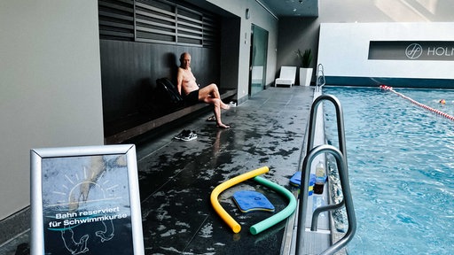 Harald Peter sitzt an einem Schwimmbecken und lacht.