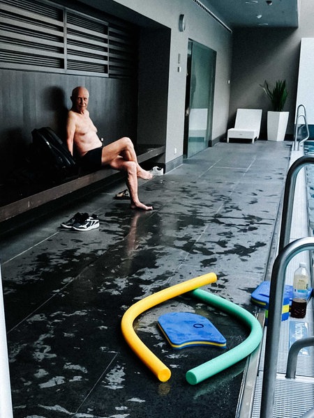 Harald Peter sitzt an einem Schwimmbecken und lacht.