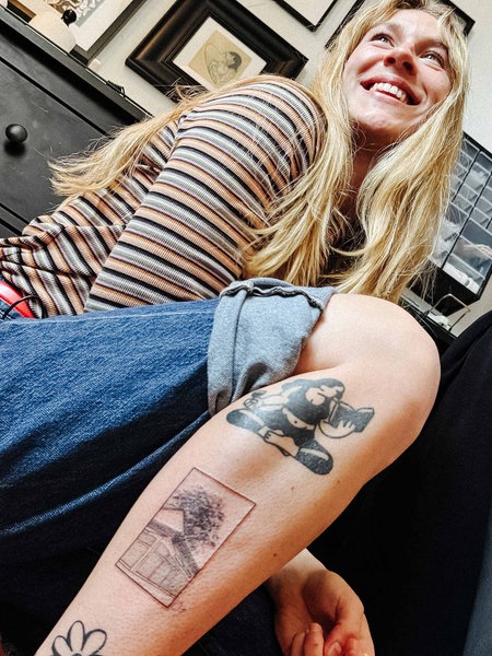v. l. Rieke Sasse und Melina Di Febo. Rieke Sasse hockt und hält ihre Wade mit dem neuen Tattoo in die Kamera.