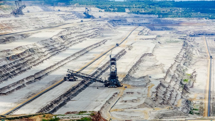 Ein Loch aus abgegrabenem Boden, in dem drei Braunkohle-Bagger stehen