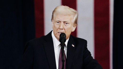 Donald Trump spricht in ein Mikrofon.