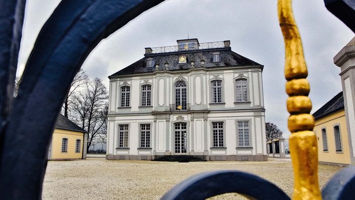 Ein weißes Schloss liegt hinter einem Tor