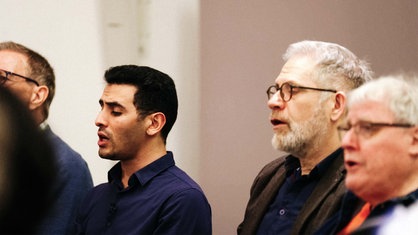Vier Männer sitzen nebeneinander und singen.