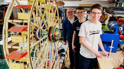 Links ein Riesenrad. Rechts daneben Alexander, Felix und Vater Frank Meinold