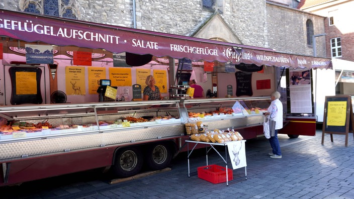 Ein Geflügelstand auf dem Paderborner Markt. Eine ältere Kundin kauft gerade Fleisch und wird bedient.